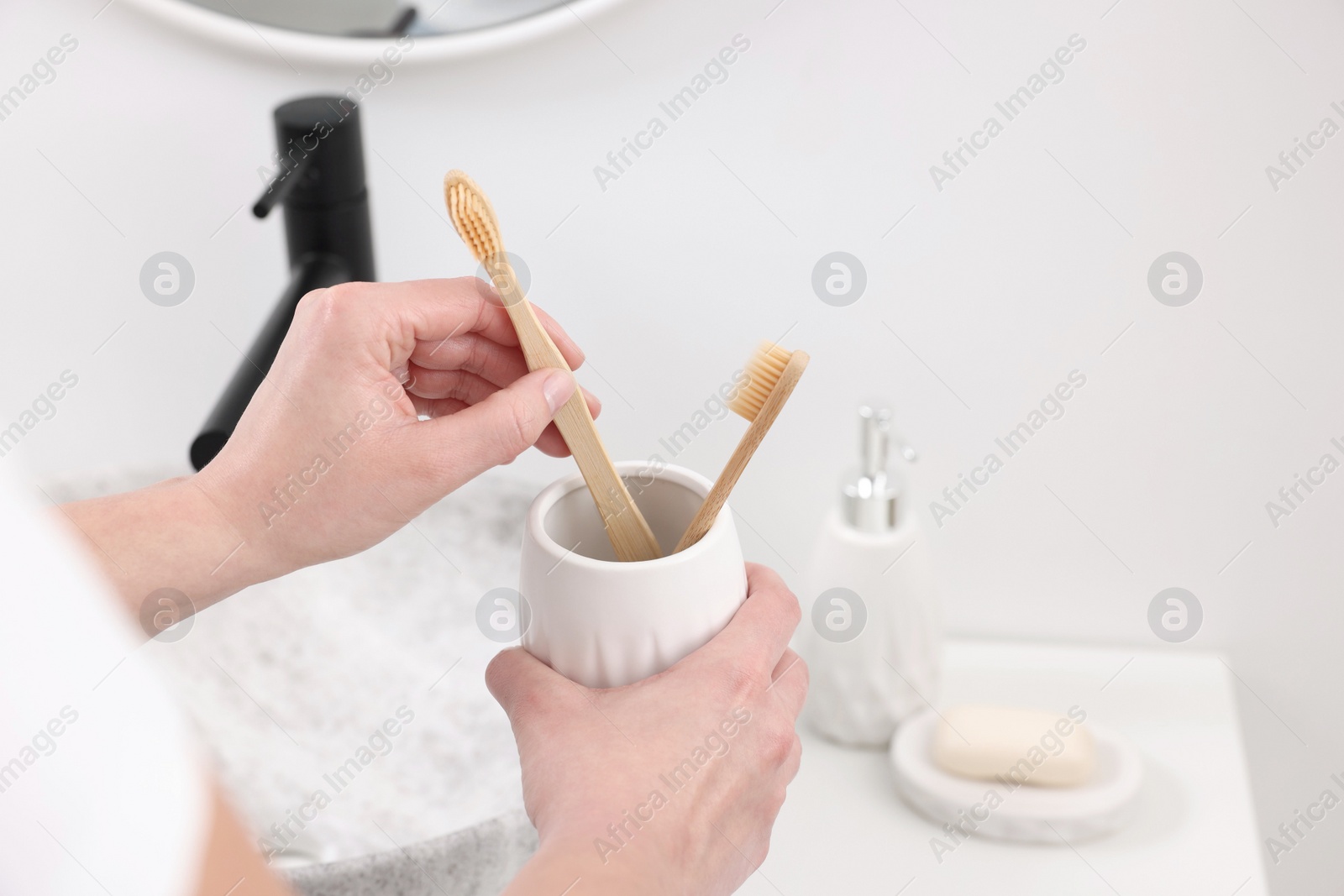 Photo of Bath accessories. Woman with toothbrushes in ceramic holder indoors, closeup and space for text