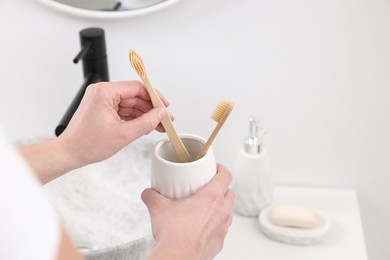 Bath accessories. Woman with toothbrushes in ceramic holder indoors, closeup and space for text