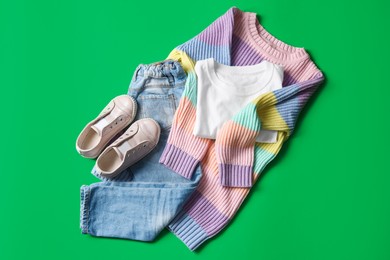 Photo of Stylish child clothes and shoes on green background, flat lay