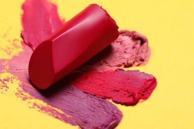 Photo of Bright lipstick and different smears on yellow background