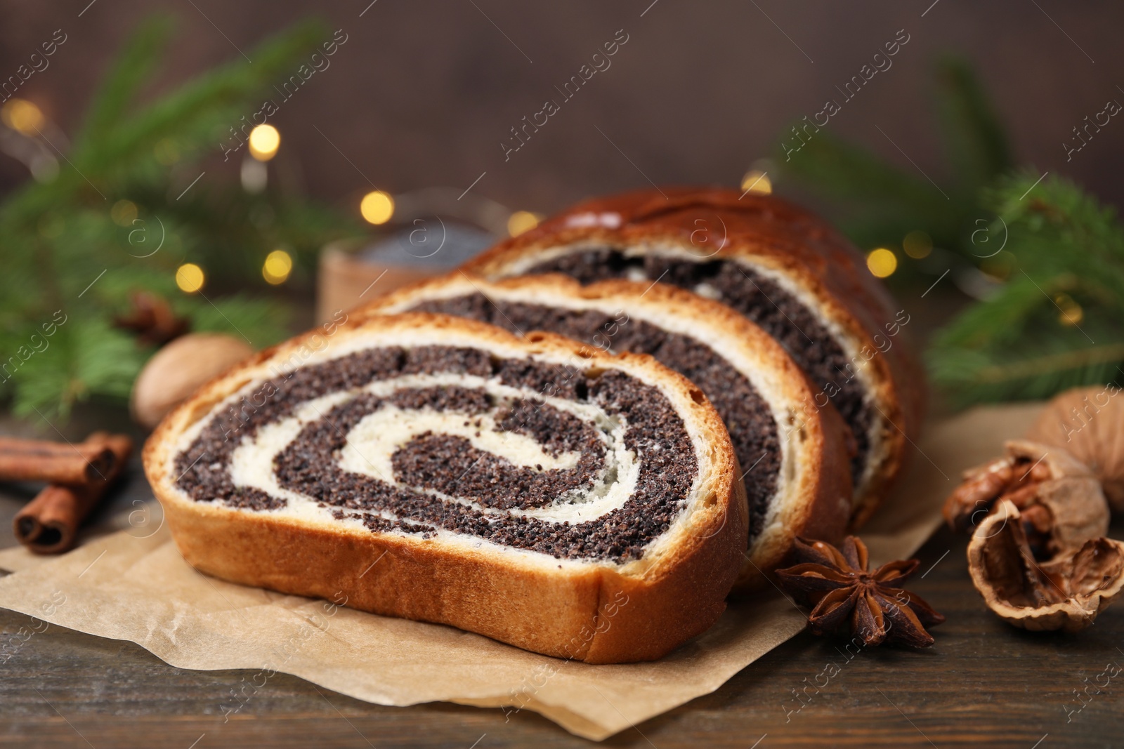 Photo of Cut poppy seed roll, anise star and walnut on wooden table, closeup. Tasty cake