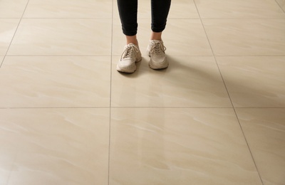 Photo of Woman standing on ceramic floor, closeup. Space for text