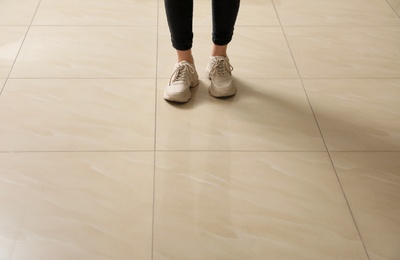 Woman standing on ceramic floor, closeup. Space for text