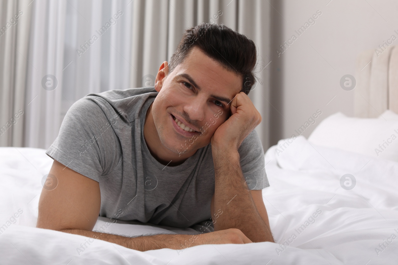 Photo of Happy man lying on bed at home