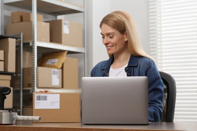 Photo of Seller with parcel and laptop in office. Online store