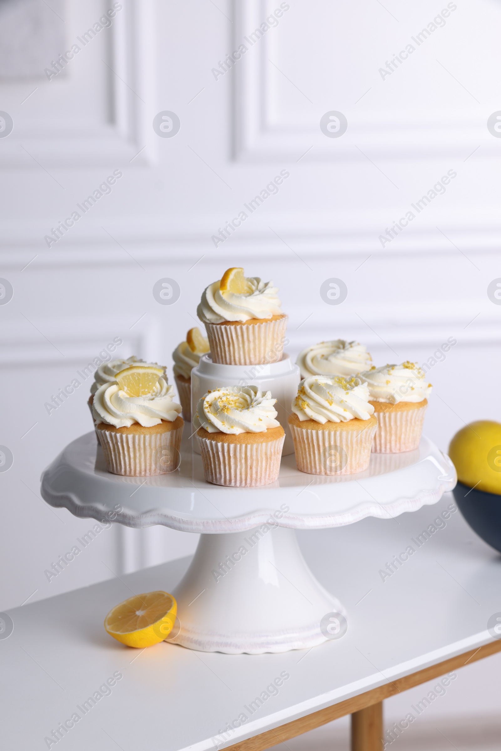 Photo of Delicious lemon cupcakes with cream on white table