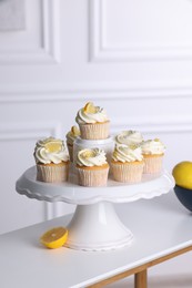 Delicious lemon cupcakes with cream on white table