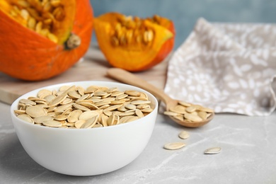 Photo of Bowl of raw pumpkin seeds on light grey marble table. Space for text