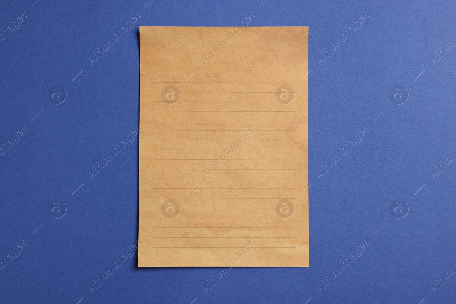 Photo of Sheet of old parchment paper on blue background, top view