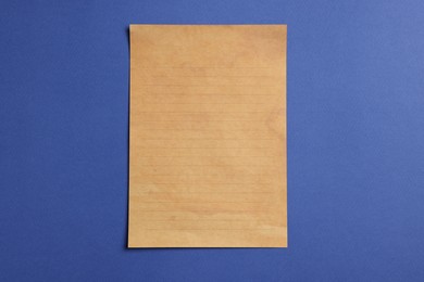 Photo of Sheet of old parchment paper on blue background, top view