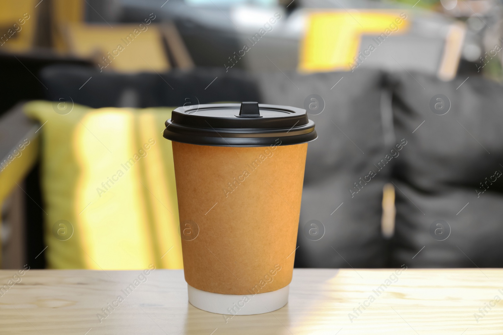 Photo of Cardboard cup with plastic lid on wooden table outdoors. Coffee to go