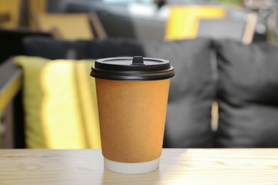Photo of Cardboard cup with plastic lid on wooden table outdoors. Coffee to go