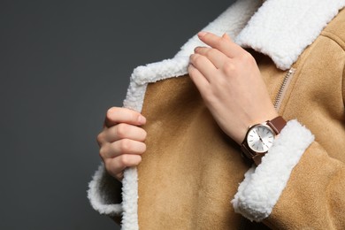 Woman wearing luxury wristwatch on grey background, closeup