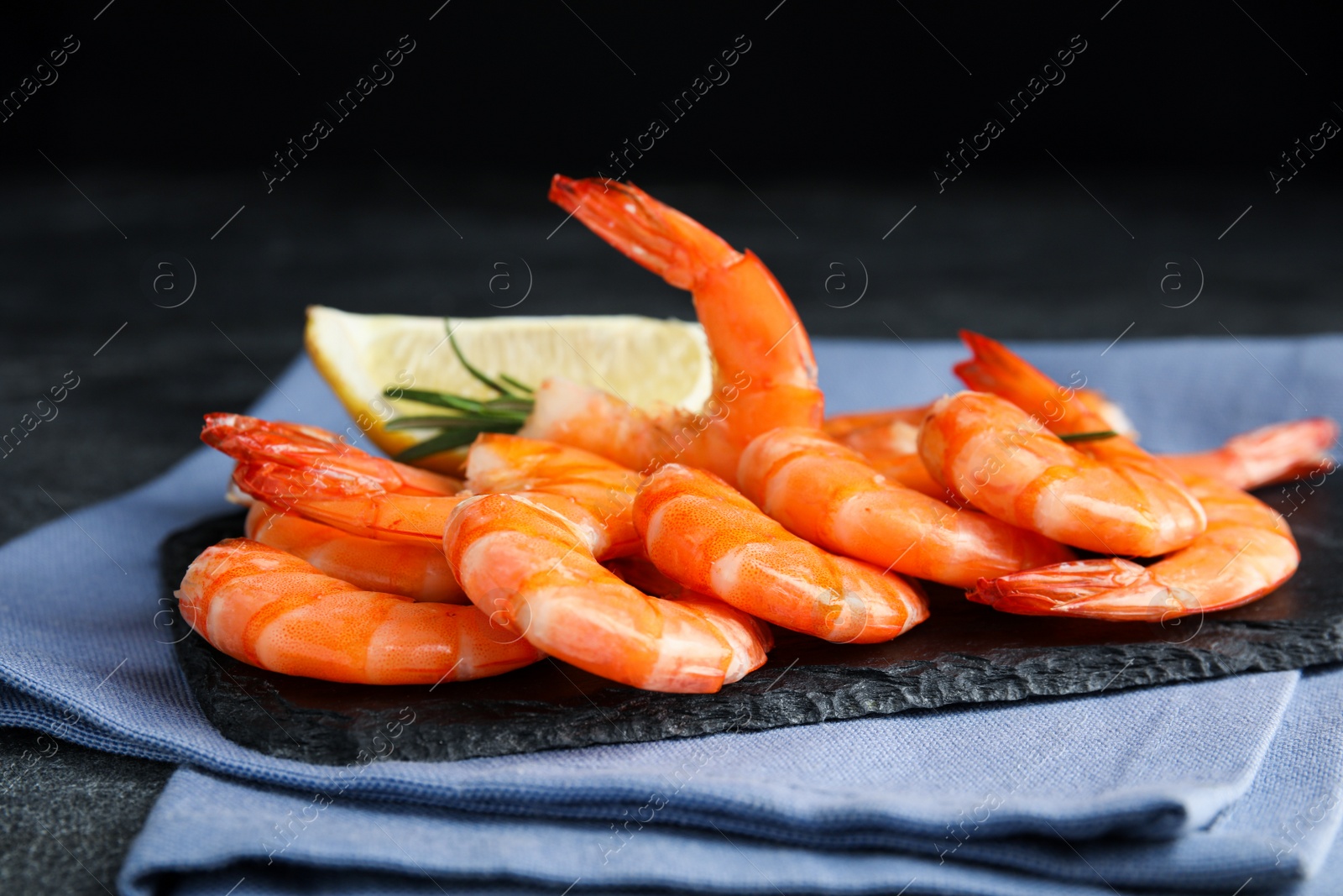 Photo of Delicious cooked shrimps with rosemary and lemon on slate board