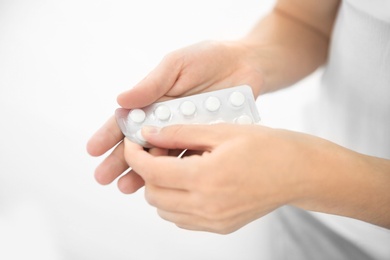 Young woman holding blister with pills, closeup