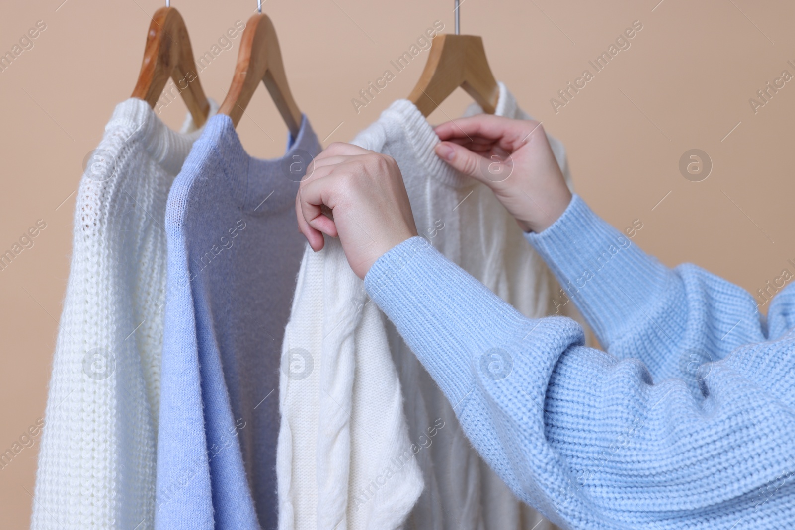 Photo of Woman taking casual sweater on beige background, closeup