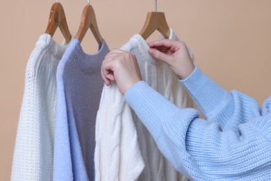 Photo of Woman taking casual sweater on beige background, closeup