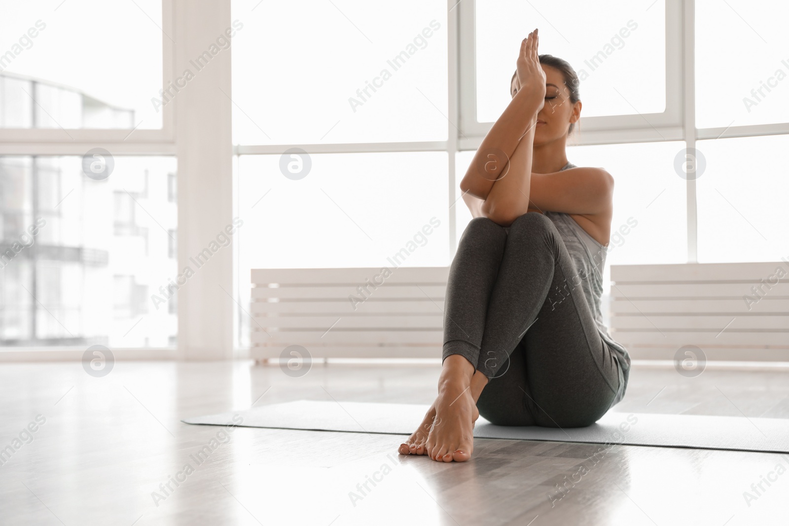 Photo of Young woman practicing eagle asana in yoga studio. Garudasana pose