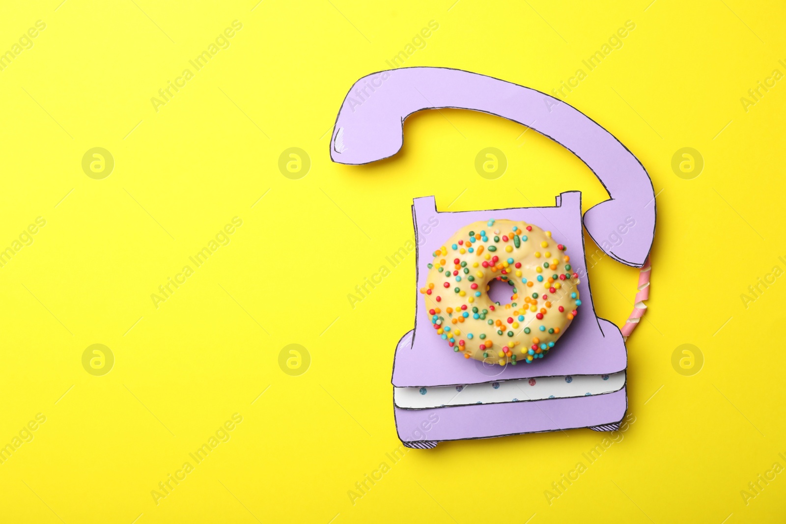 Photo of Vintage phone made with donut on yellow background, top view. Space for text
