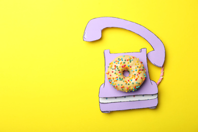 Vintage phone made with donut on yellow background, top view. Space for text