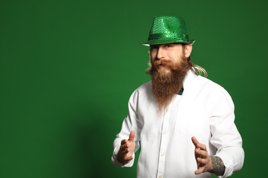Photo of Bearded man in green hat on color background, space for text. St. Patrick's Day celebration