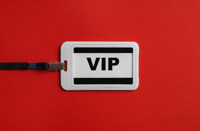 Photo of Plastic vip badge on red background, top view