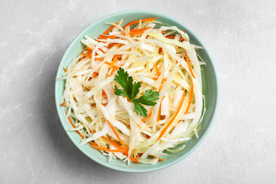 Photo of Tasty salad with cabbage and carrot on light grey marble table, top view