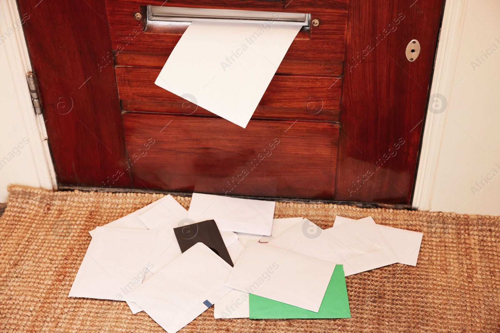 Photo of Wooden door with mail slot and many envelopes indoors