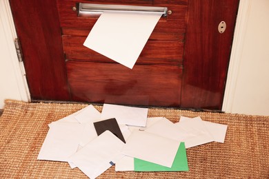 Wooden door with mail slot and many envelopes indoors