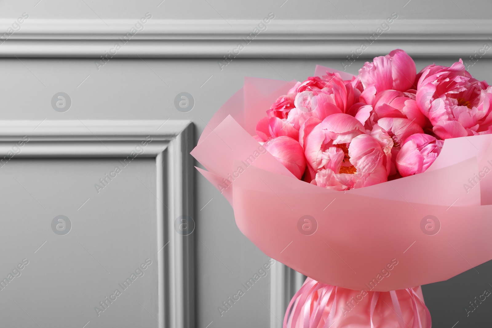 Photo of Bouquet of beautiful pink peonies near grey wall. Space for text