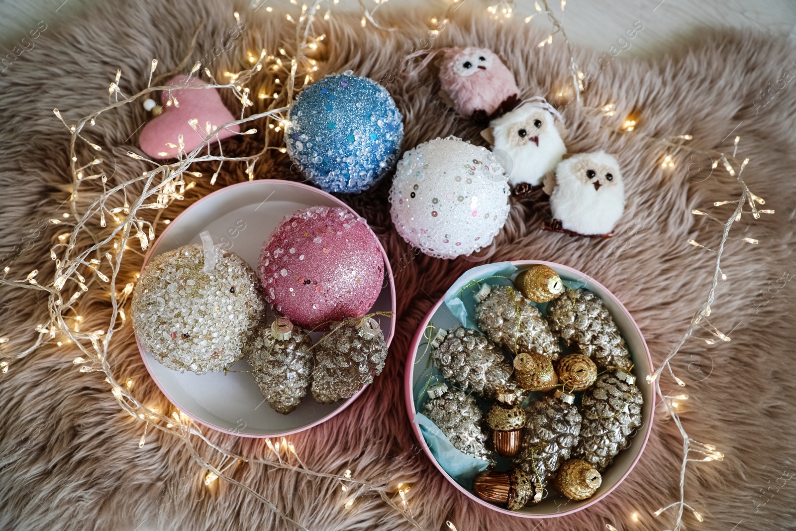 Photo of Beautiful Christmas tree baubles, toys and fairy lights on faux fur, above view