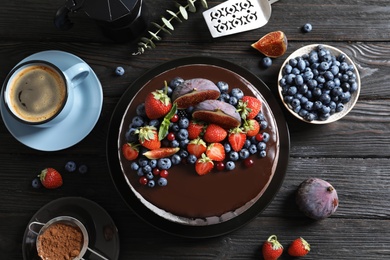 Photo of Fresh delicious homemade chocolate cake with berries on dark table, flat lay