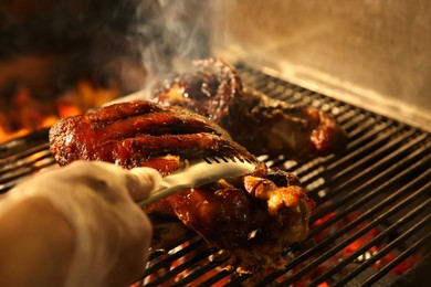 Photo of Chef cooking pork foreshanks in oven with burning firewood, closeup
