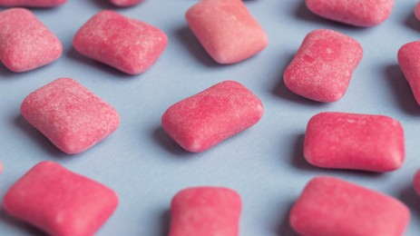 Photo of Many sweet chewing gums on light blue background, closeup