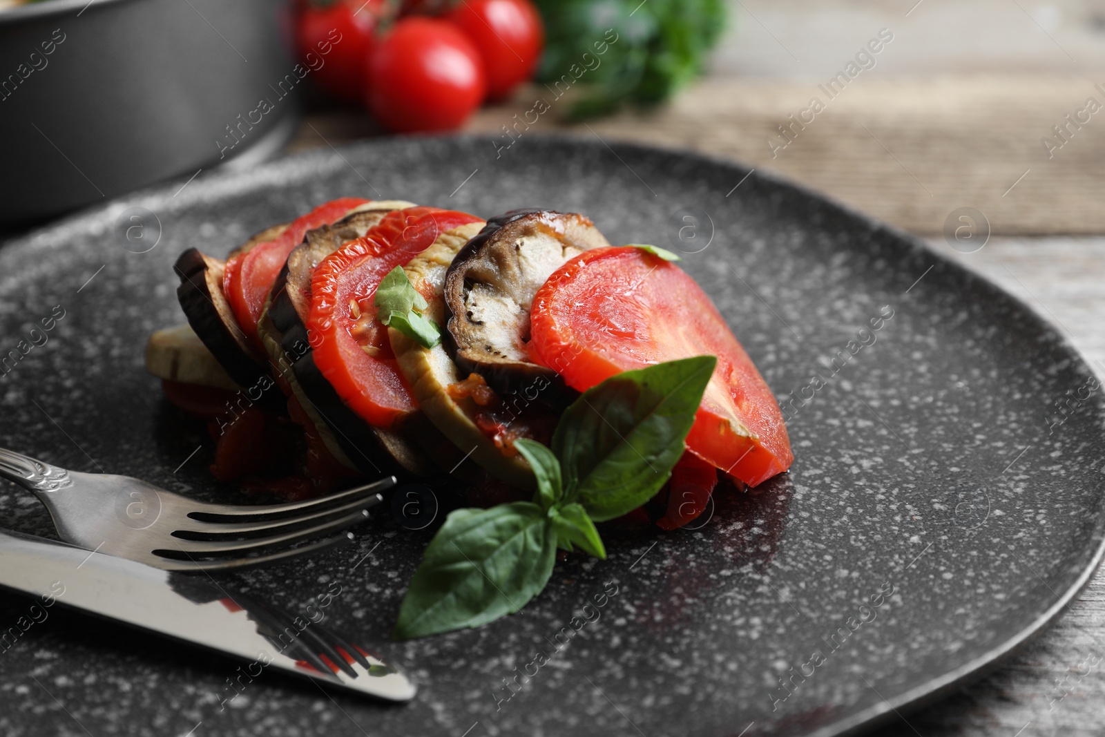 Photo of Delicious ratatouille served with basil on wooden table, closeup