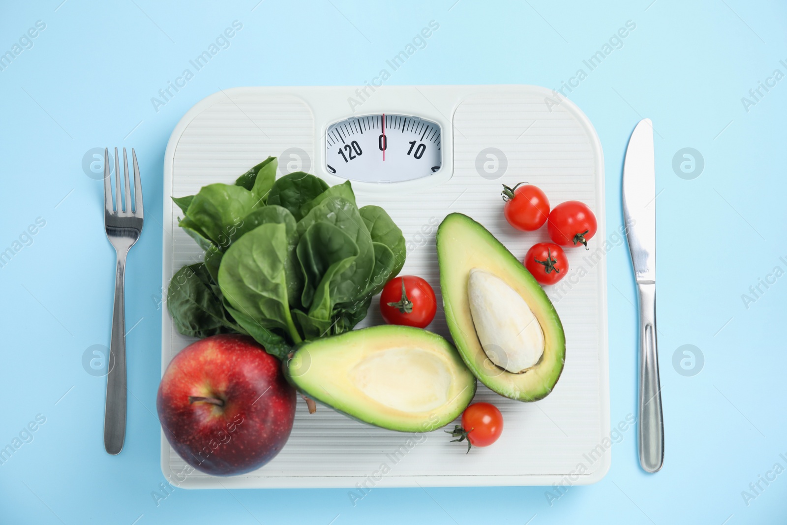 Scales, healthy food and cutlery on light blue background, flat lay Photo of Scales, healthy food and cutlery on light blue background, flat lay