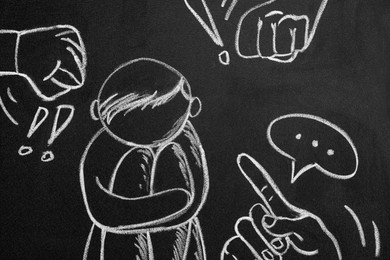 Photo of People bullying sad human drawn on blackboard