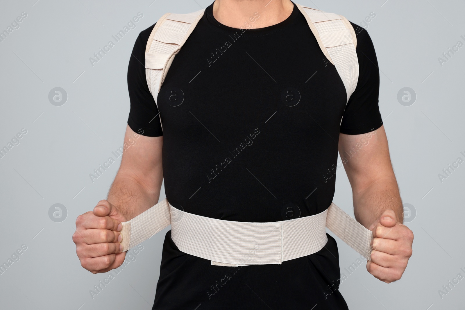 Photo of Closeup view of man with orthopedic corset on grey background