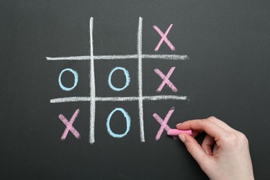 Woman playing tic tac toe on chalkboard, closeup