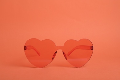 Heart shaped coral sunglasses on orange background