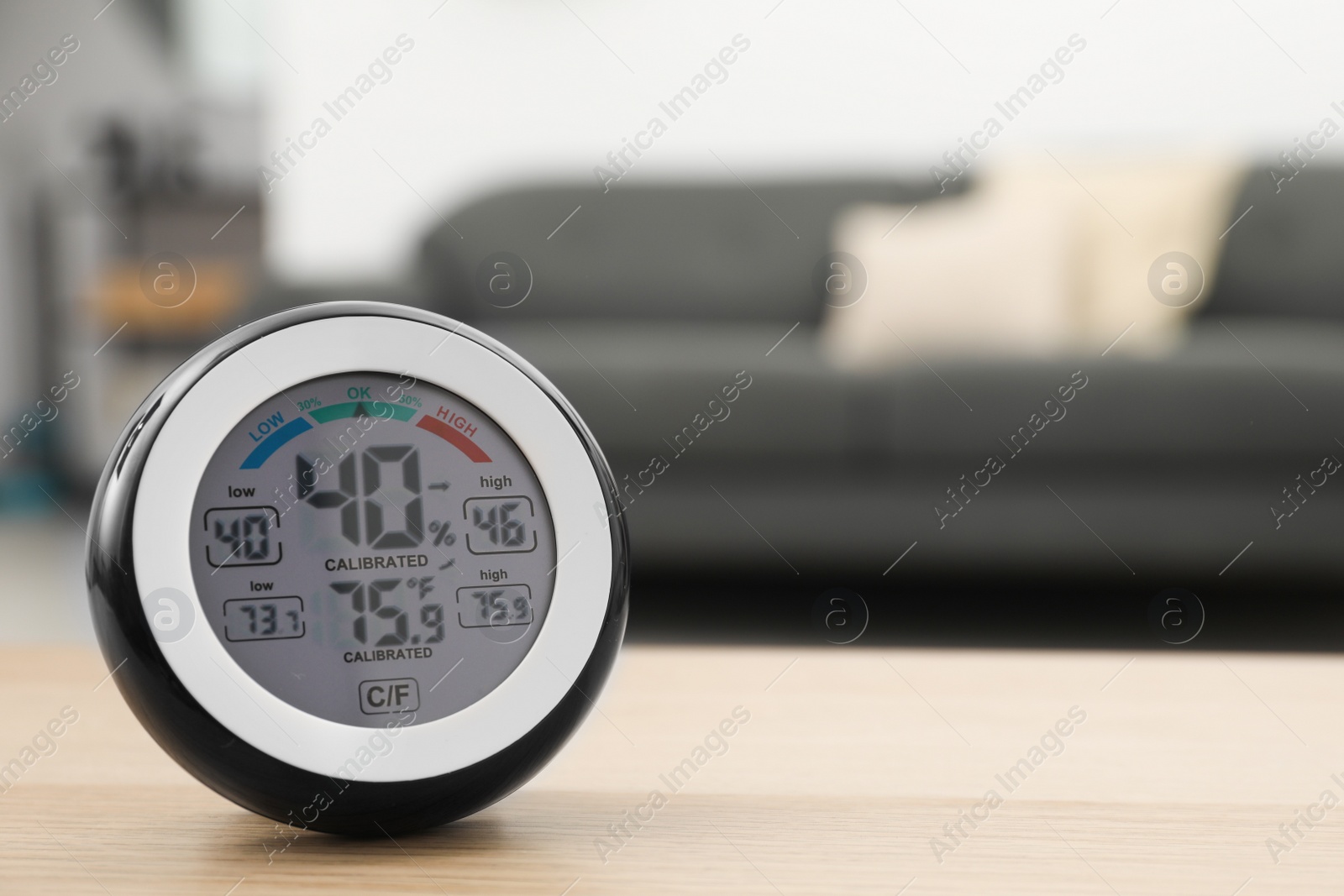 Photo of Digital hygrometer with thermometer on wooden table in room. Space for text