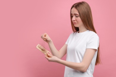 Photo of Woman untangling her lost hair from comb on pink background, space for text. Alopecia problem