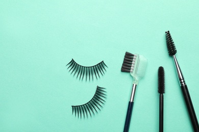 False eyelashes and brushes on turquoise background, flat lay. Space for text