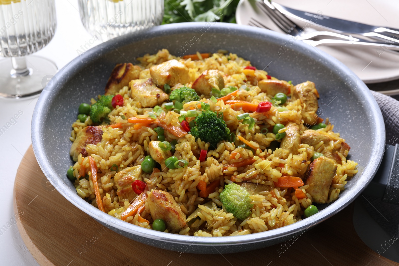 Photo of Tasty rice with meat and vegetables in frying pan on white table, closeup