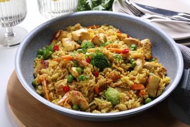 Photo of Tasty rice with meat and vegetables in frying pan on white table, closeup