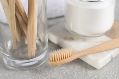 Bamboo toothbrushes and jar of baking soda on light grey table, closeup
