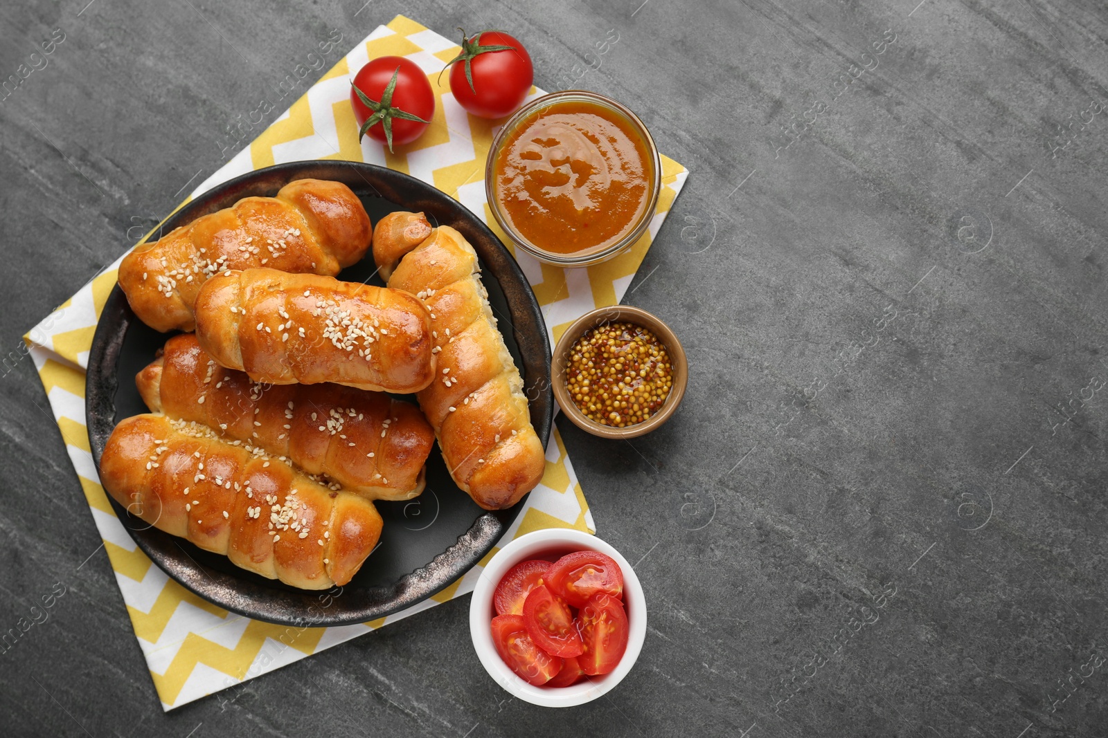 Photo of Delicious sausage rolls and ingredients on grey table, flat lay. Space for text