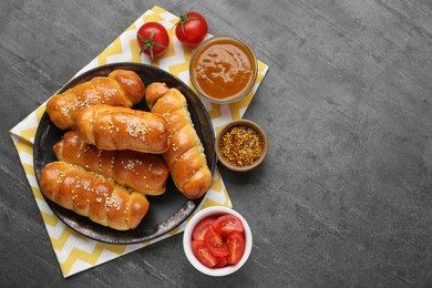 Photo of Delicious sausage rolls and ingredients on grey table, flat lay. Space for text