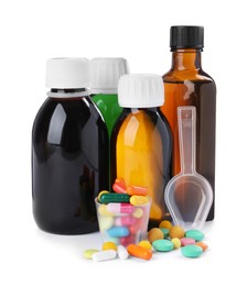 Photo of Bottles of syrups, measuring cup, plastic spoon with pills on white background. Cough and cold medicine