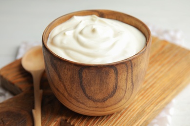 Wooden bowl with creamy yogurt served on table